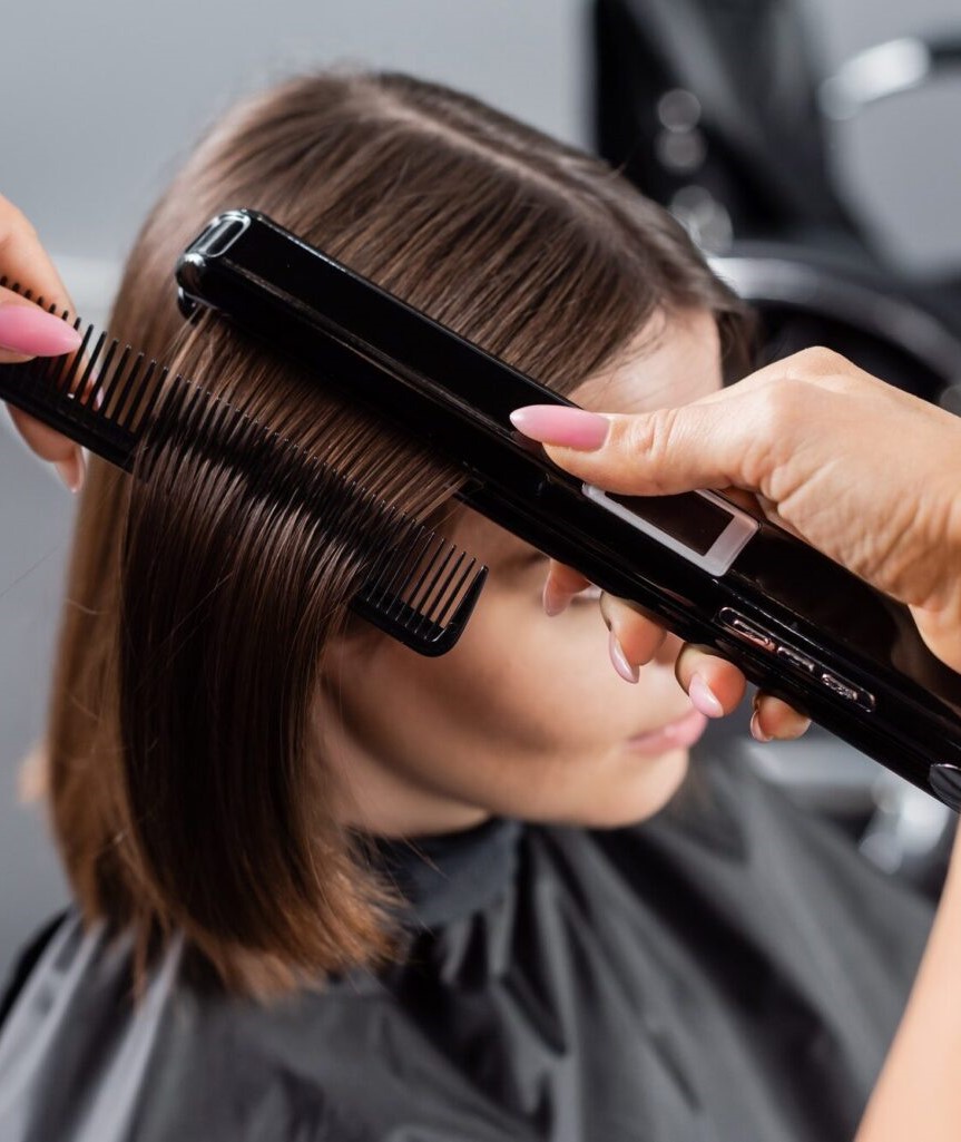 Hair stylist straightening client’s hair at SPY Salon NCR